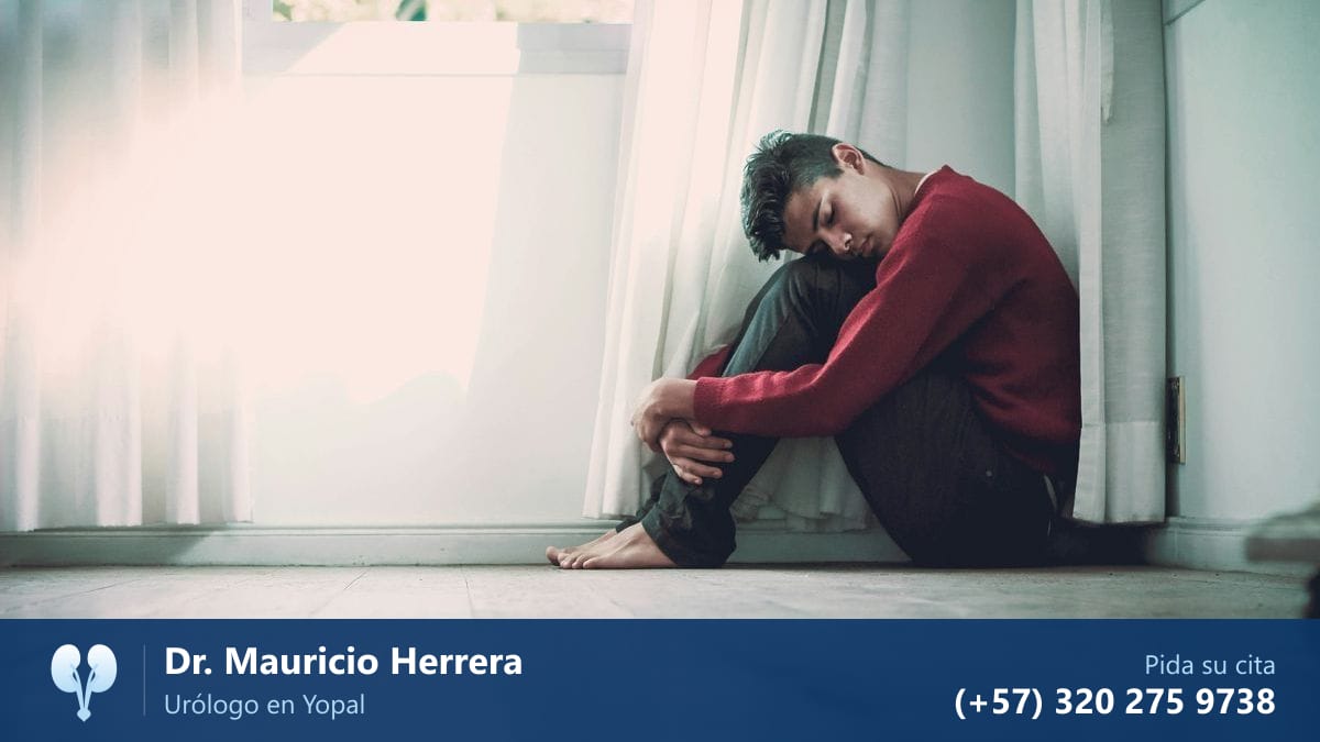 Hombre joven preocupado sentado en el suelo junto a la ventana, disfunción eréctil. Dr. Mauricio Herrera, urólogo en Yopal