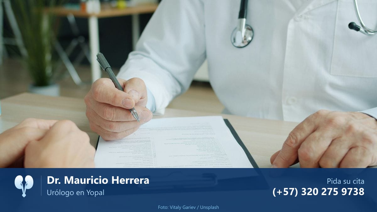 Médico con bata revisando unos papeles en consulta, con el paciente delante. Dr. Mauricio Herrera, urólogo en Yopal