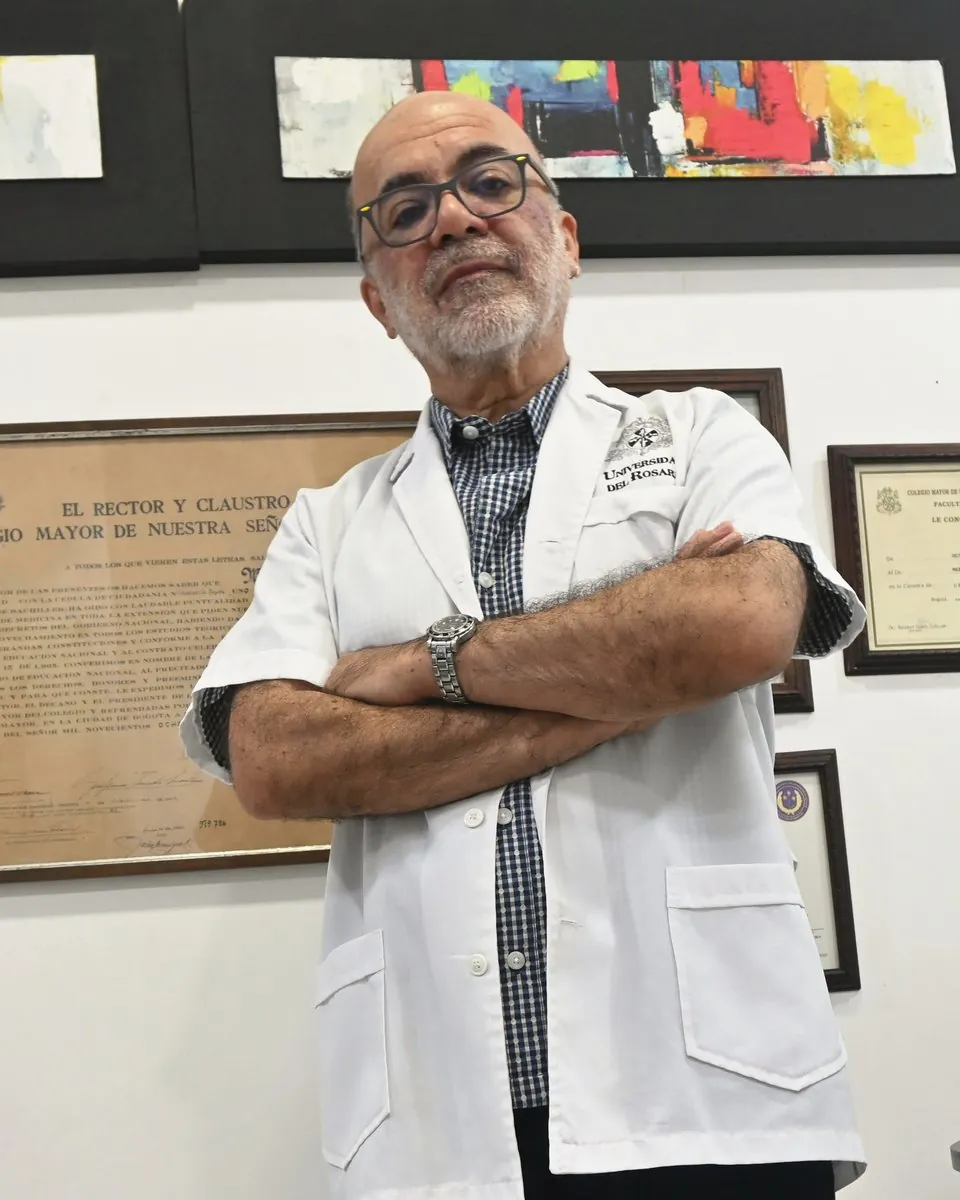 El Dr. Mauricio Herrera de brazos cruzados frente a su diploma de la Universidad del Rosario